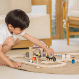 Child playing with a train on a PlanToys city transit rail and road playset