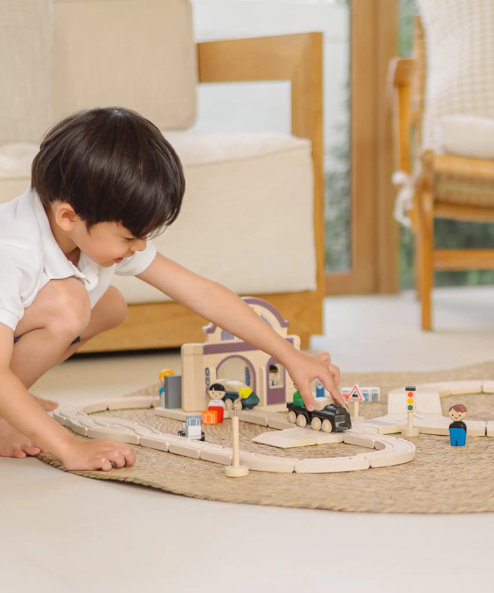 Child playing with a train on a PlanToys city transit rail and road playset