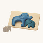 PlanToys Elephant Puzzle on a plain background, the smallest grey coloured elephant can be seen taken out of the puzzle base. 