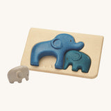 PlanToys Elephant Puzzle on a plain background, the smallest grey coloured elephant can be seen taken out of the puzzle base. 