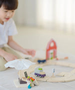 PlanToys market stall set standing next to a roadway