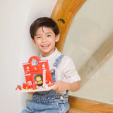 Child holding a PlanToys wooden fire station set with figures showing scale
