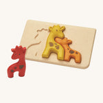 The PlanToys Giraffe Puzzle is an adorable puzzle for little ones. The set comes with a red, a yellow and an orange giraffe which when put together in the puzzle board, look like they're all nuzzling together. The image is on a cream background