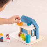 Back of Child playing with the PlanToys wooden blue house set showing the wooden furniture and family figures