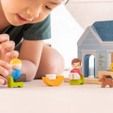 PlanToys wooden blue house set showing a child picking up a wooden father figure 