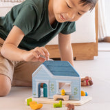 Child playing with the PlanToys wooden blue house set showing all furniture in front 