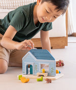 Child playing with the PlanToys wooden blue house set showing all furniture in front 