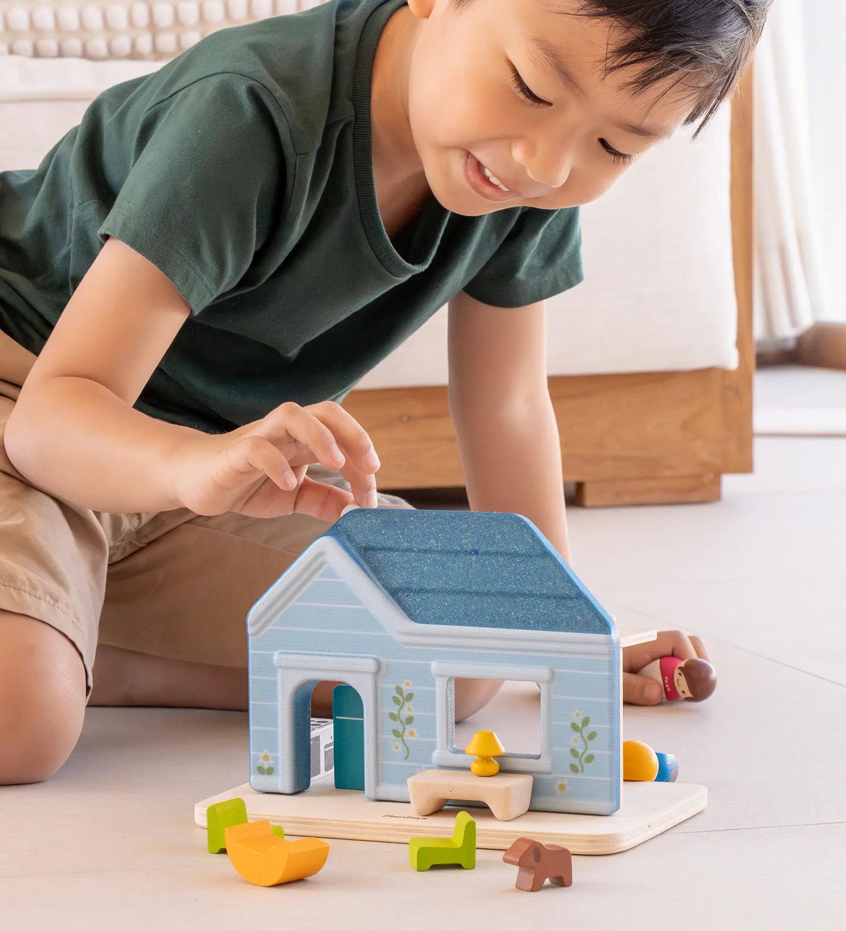 Child playing with the PlanToys wooden blue house set showing all furniture in front 