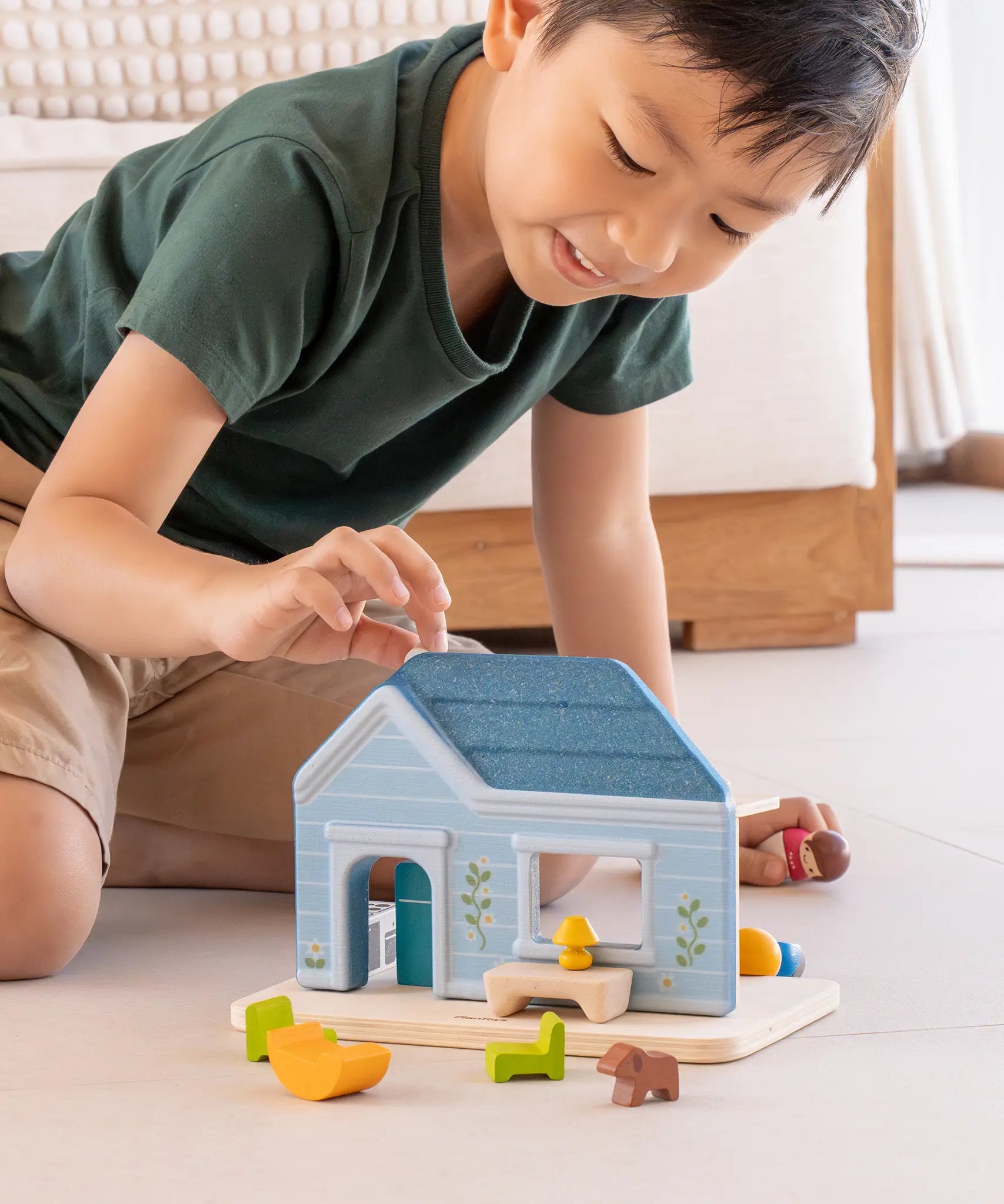Child playing with the PlanToys wooden blue house set showing all furniture in front 