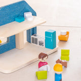 Back of the PlanToys wooden blue house set showing small loose furniture, figures and kitchen appliances