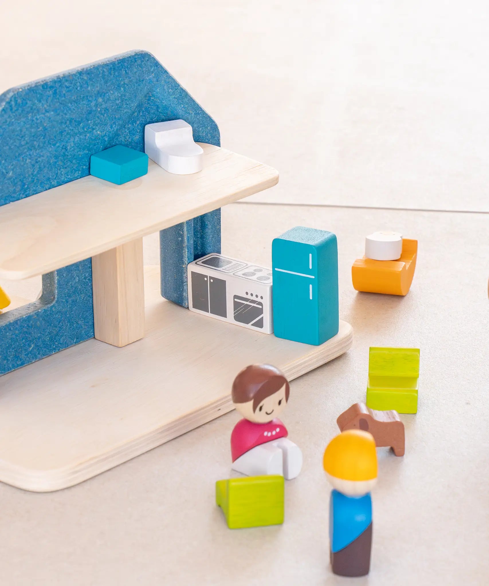 Back of the PlanToys wooden blue house set showing small loose furniture, figures and kitchen appliances