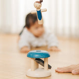 Adult hand pressing down on the base launching the PlanToys gymnast peg doll