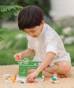 Child holding animal figures from the PlanToys pet shop outdoors showing scale 