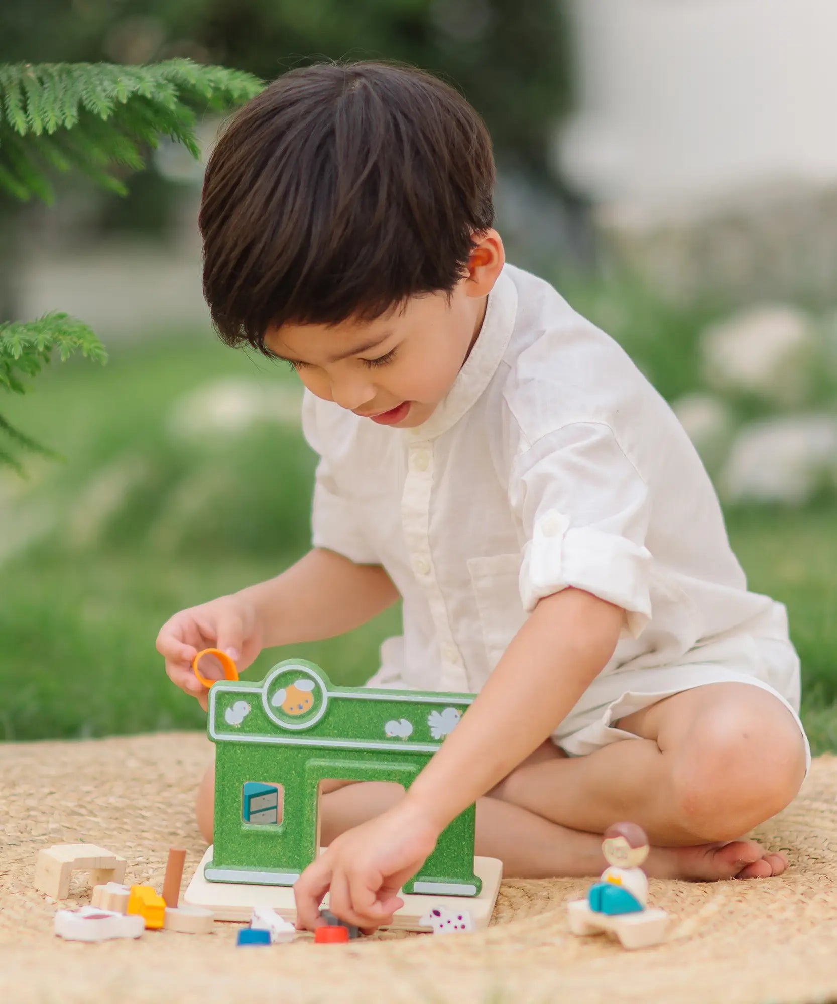 Child holding animal figures from the PlanToys pet shop outdoors showing scale 