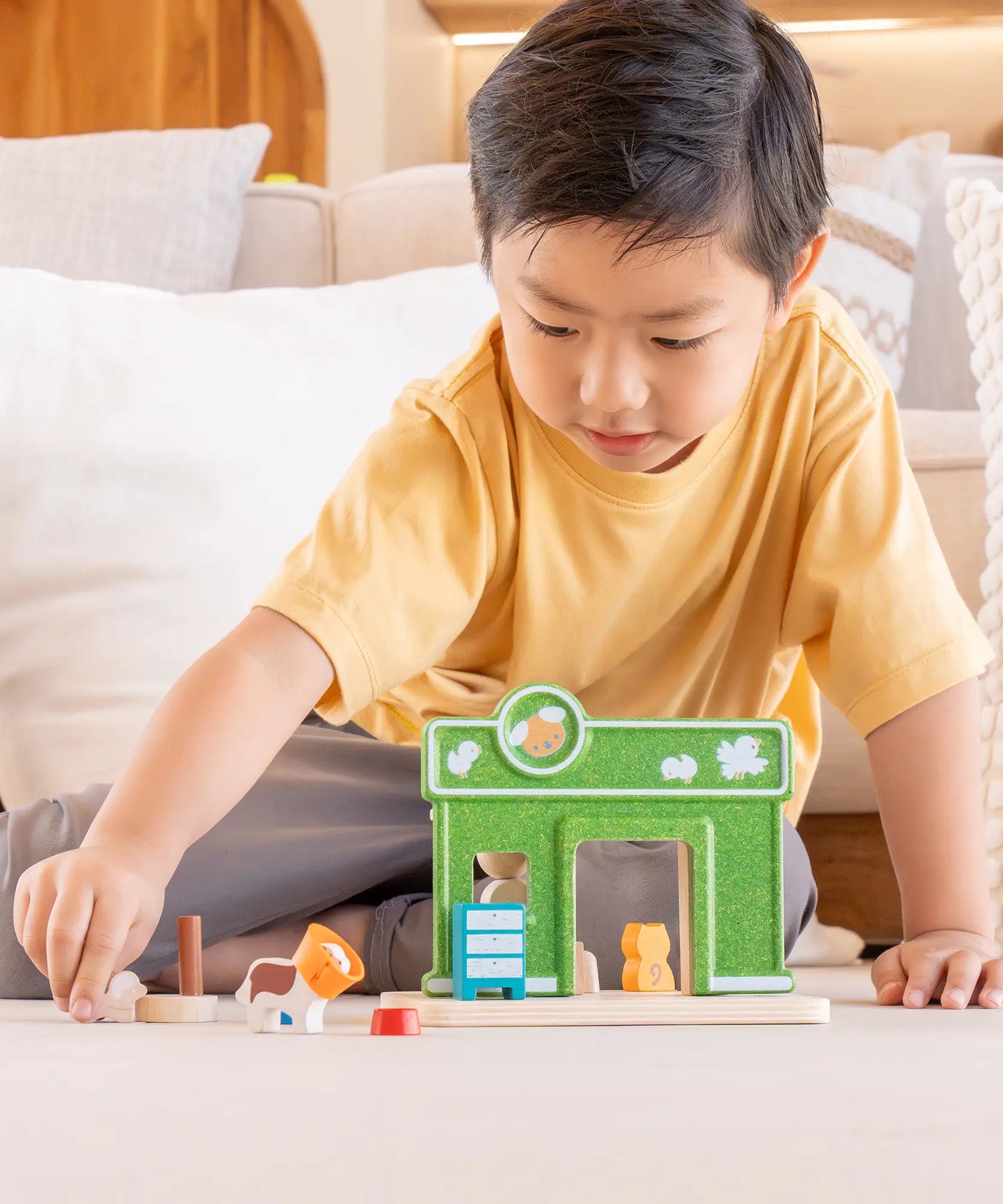 Child playing with a animal figure next to the PlanToys pet shop play set
