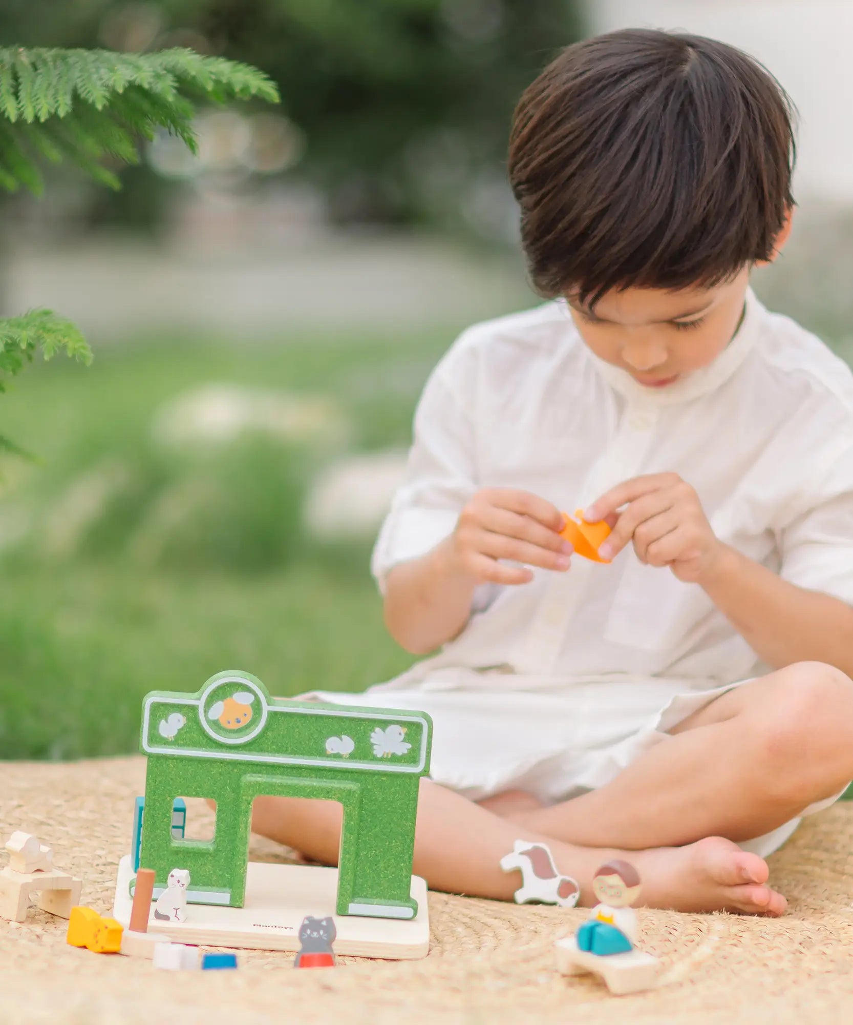 Child playing with the PlanToys pet shop play set outdoors