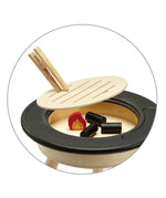 A closer view of the inside of the PlanToys BBQ play set, showing the removable wooden grill, the coal blocks and the wooden flame block inside. The grill section can be removed by using the wooden tongues