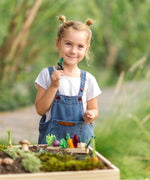 Child holding a loose veg piece with a PlanToys seedling patch on a large planter