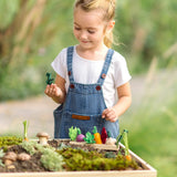 PlanToys wooden seedling planter with veg sitting on top and a child picking up a loose felted veg piece