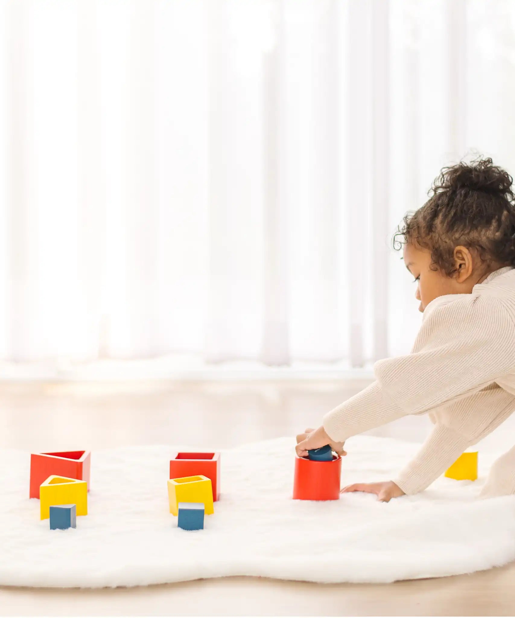 Child playing with PlanToys nesting  wooden toys, triangle, square and circle. 
