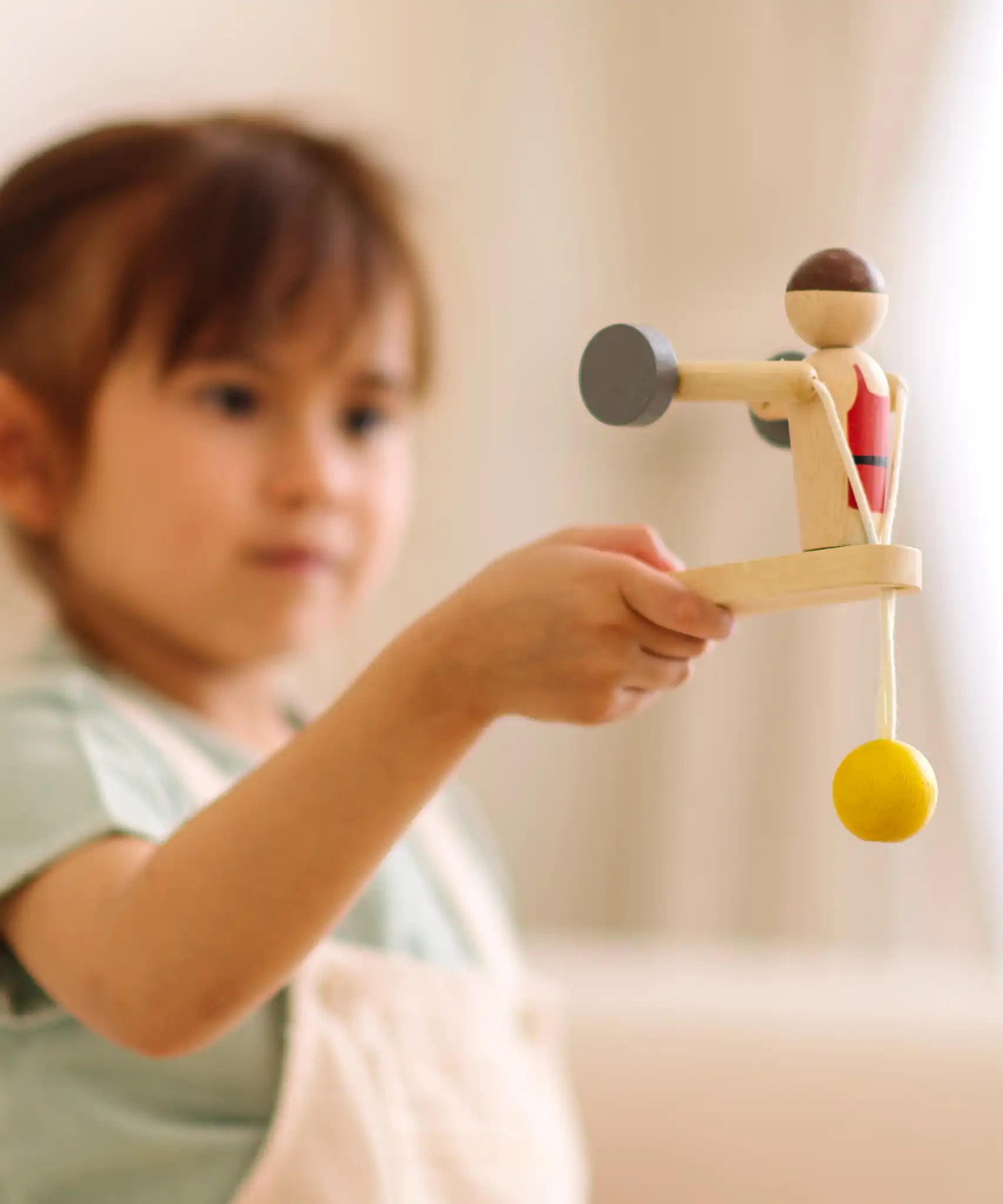 Child playing with the PlanToys Weightlifting Acrobat wooden toy.