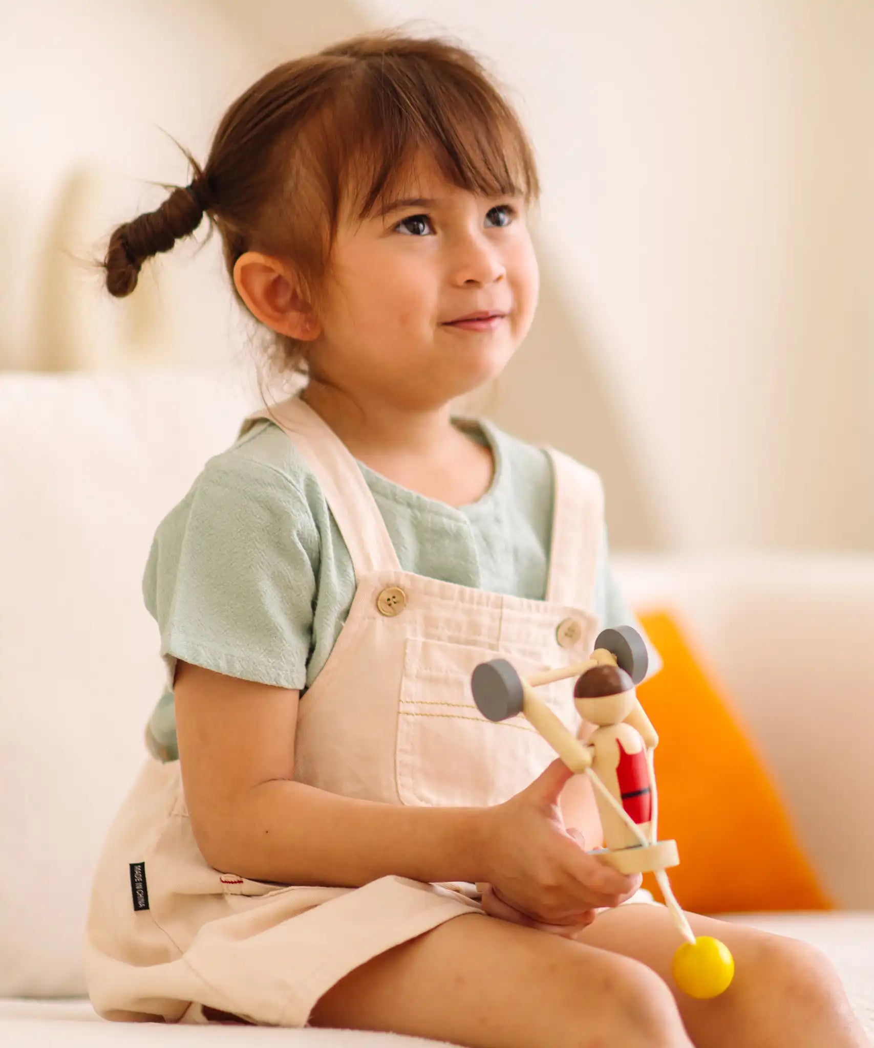 Child playing with the PlanToys Weightlifting Acrobat wooden toy.