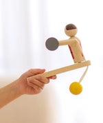 PlanToys Weightlifting Acrobat wooden toy shown in a child's hand.