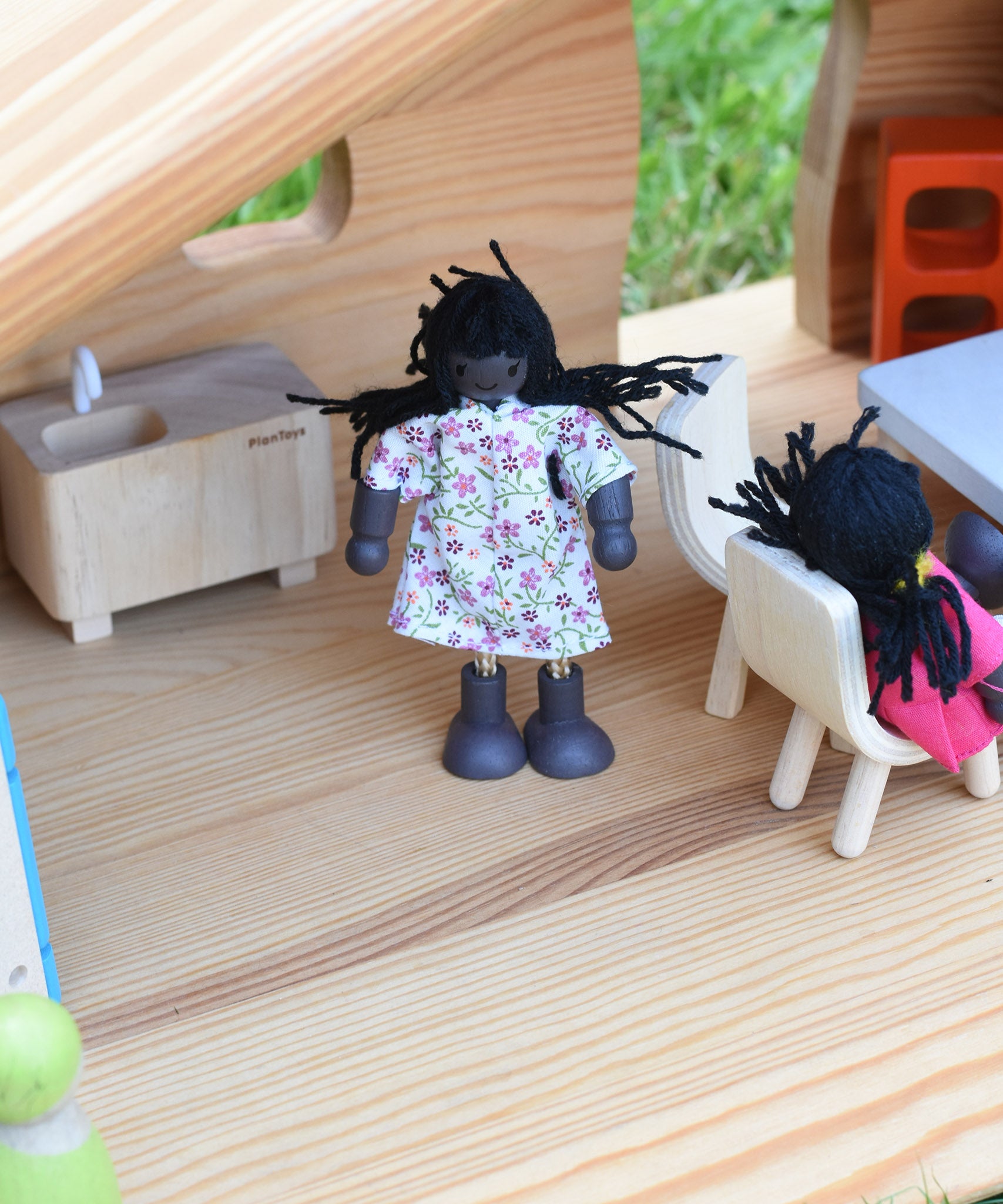 A doll from the PlanToys doll house family set placed in an Ostheimer dolls house.