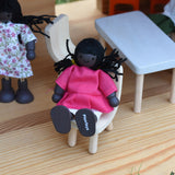 A doll from the PlanToys doll house family set placed in an Ostheimer dolls house.