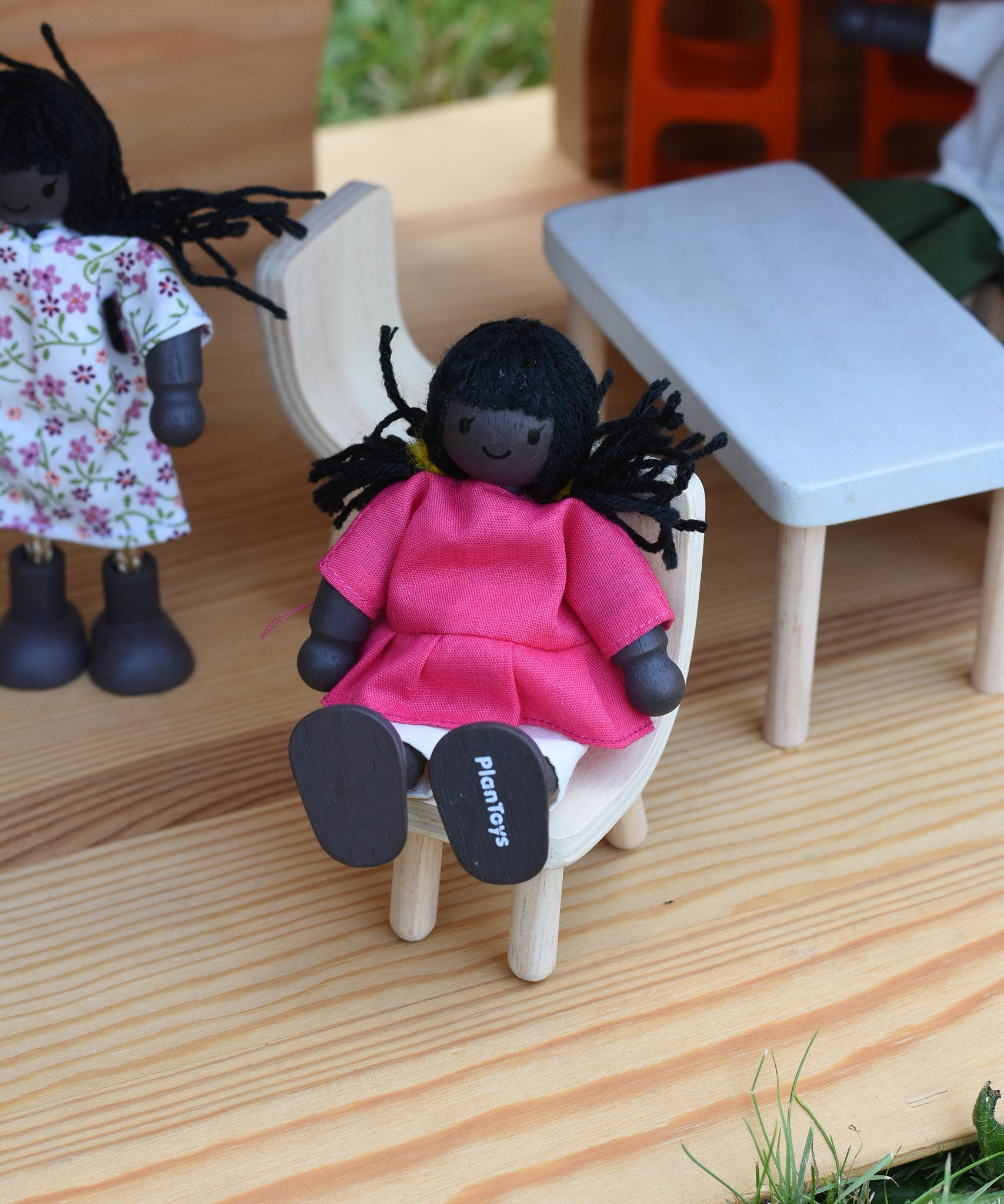 A doll from the PlanToys doll house family set placed in an Ostheimer dolls house.