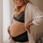 A person wearing the Lola & Lykke Core Relief Pregnancy Support Belt, with their hand on their bump