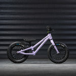 A side profile view of the Early Rider Big Foot Balance Bike - Violet Haze, on a grey textured background