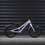 A side profile view of the Early Rider Big Foot Balance Bike - Violet Haze, on a grey textured background