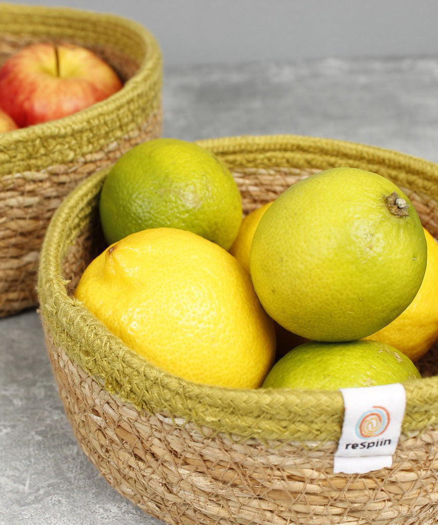 Close up of fruit inside the Respiin set of 2 natural shallow seagrass jute baskets with green rim.