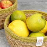 Close up of fruit inside the Respiin set of 2 natural shallow seagrass jute baskets with green rim.