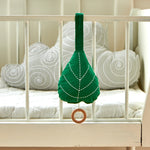 The Roommate Leaf Lullaby Music Mobile is attached to the outside of a white crib with a grey Roommate cloud cushion inside the crib