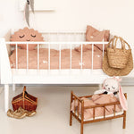 A baby's bed with the Roommate Rabbit Bedding Set is set behind a small dolls bed with the Roommate Doll Bedding Set - Rabbit inside. There is a white Roommate rabbit teddy inside the dolls bed
