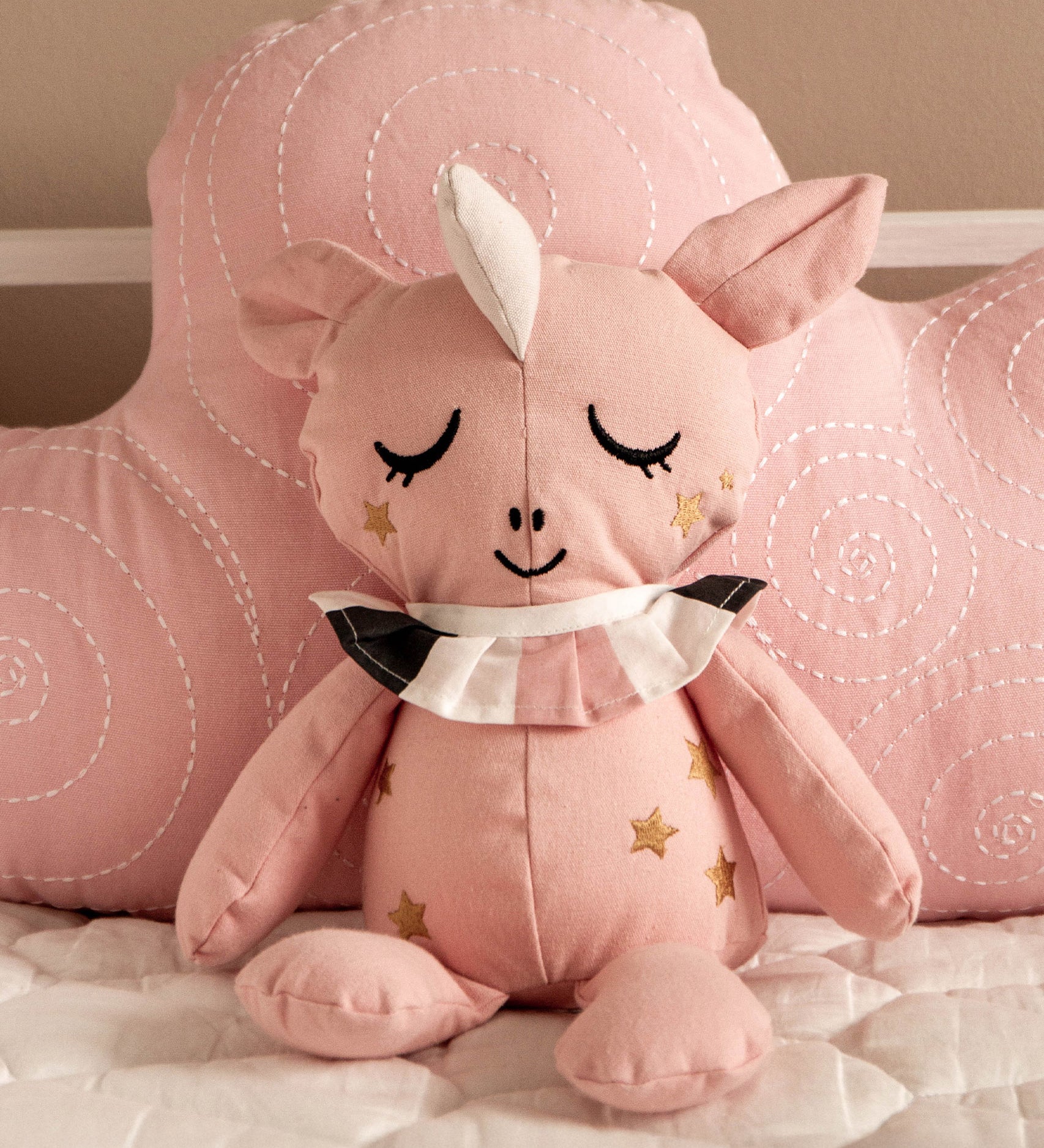 Roommate Canvas Doll Uni The Unicorn is propped up by a pink Roommate cloud cushion/pillow