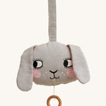 Roommate Musical Baby Mobile - Bunny, in grey. Shaped as a bunny face with pink cheeks, two floppy ears and a pull cord with a wooden hoop, on a cream background