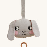 Roommate Musical Baby Mobile - Bunny, in grey. Shaped as a bunny face with pink cheeks, two floppy ears and a pull cord with a wooden hoop, on a cream background