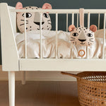 The Roommate Musical Baby Mobile - Leopard and Roommate Leopard cushion on a baby cot bed, with a basket underneath
