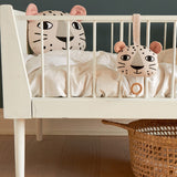 The Roommate Musical Baby Mobile - Leopard and Roommate Leopard cushion on a baby cot bed, with a basket underneath