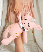 A child holding Roommate Canvas Doll Uni The Unicorn in their hand, down at their side