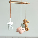 The Roommate Sealife Hanging Mobile hung above a crib with light blue background