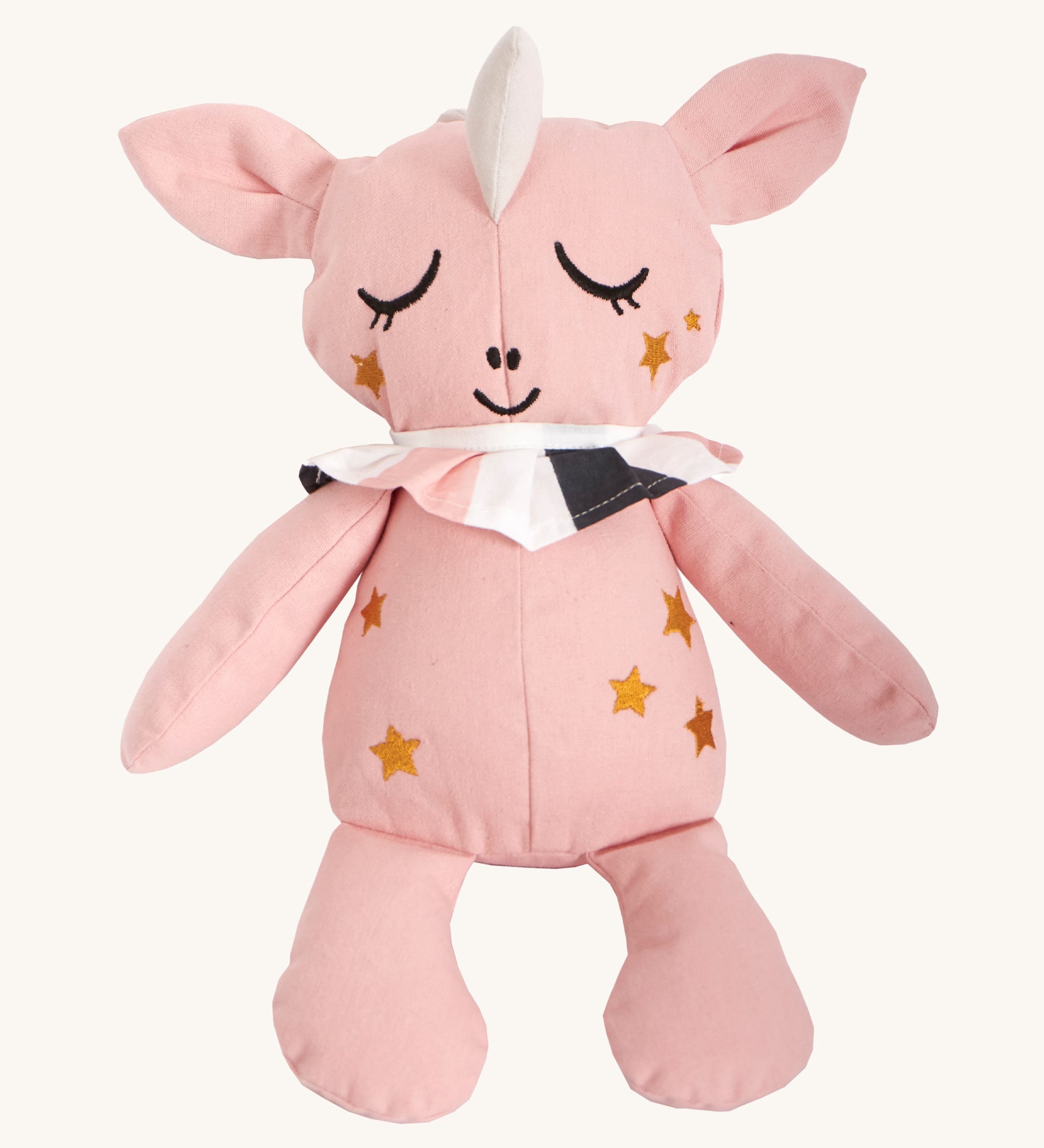 Roommate Canvas Doll Uni The Unicorn, is made from pink organic cotton and as a white unicorn horn, gold embroidered stars on its face and body, sleepy embroidered eyes and a pink, white and dark grey collar round its neck. On a cream background