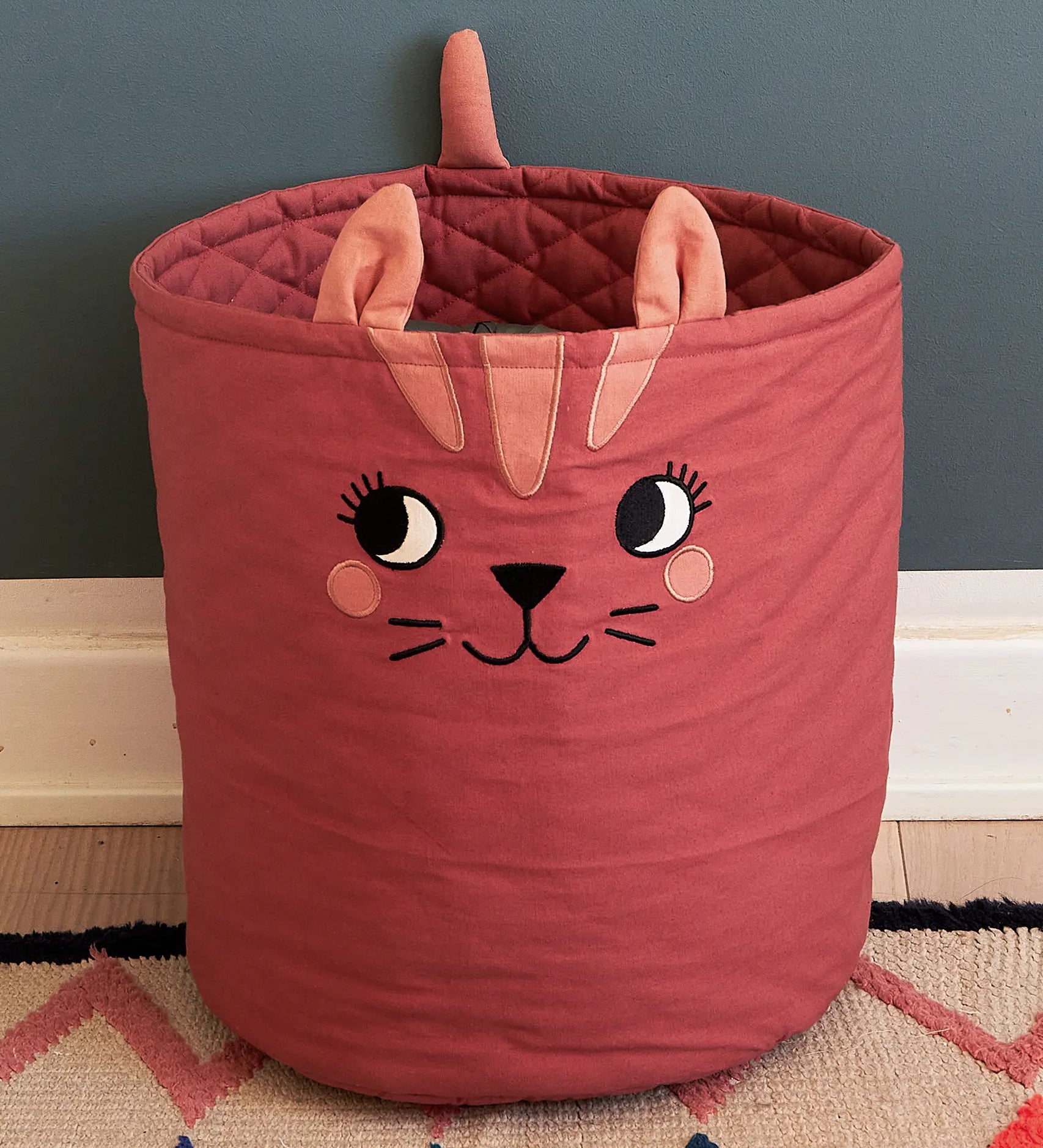 Large Roommate organic cotton storage cat basket in red with standing on a rug showing quilted finish on the inside