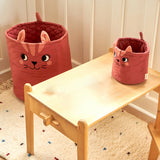 The large and mini Roommate organic cotton storage cat basket in red standing in a playroom showing size comparison