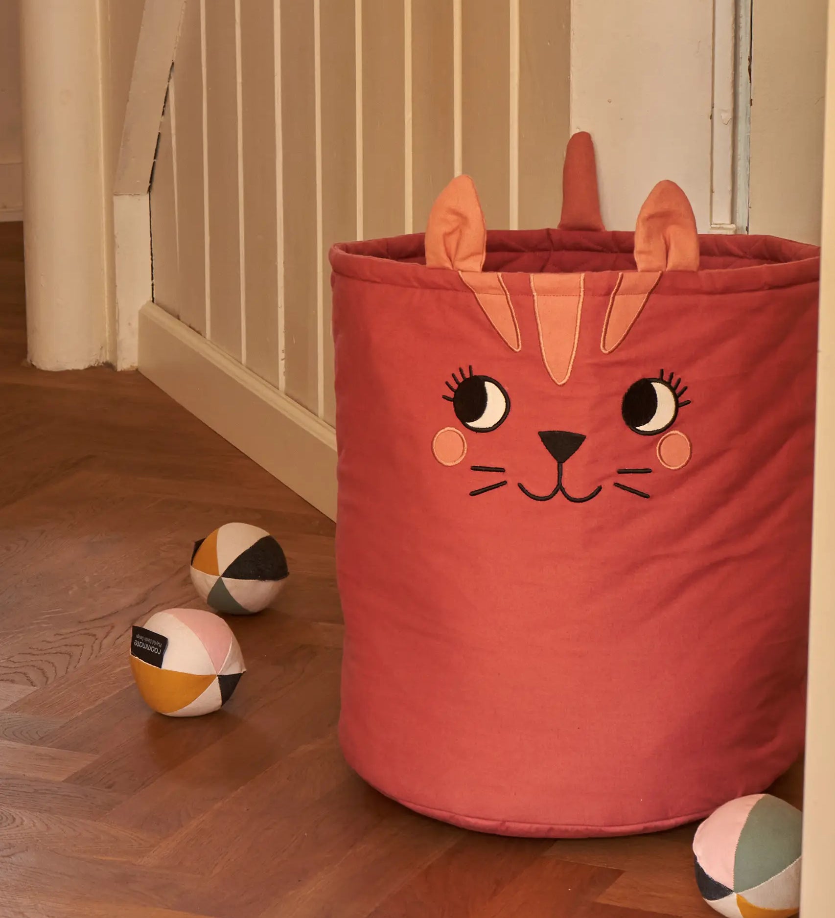 Large Roommate organic cotton storage cat basket in red standing next to sensory balls