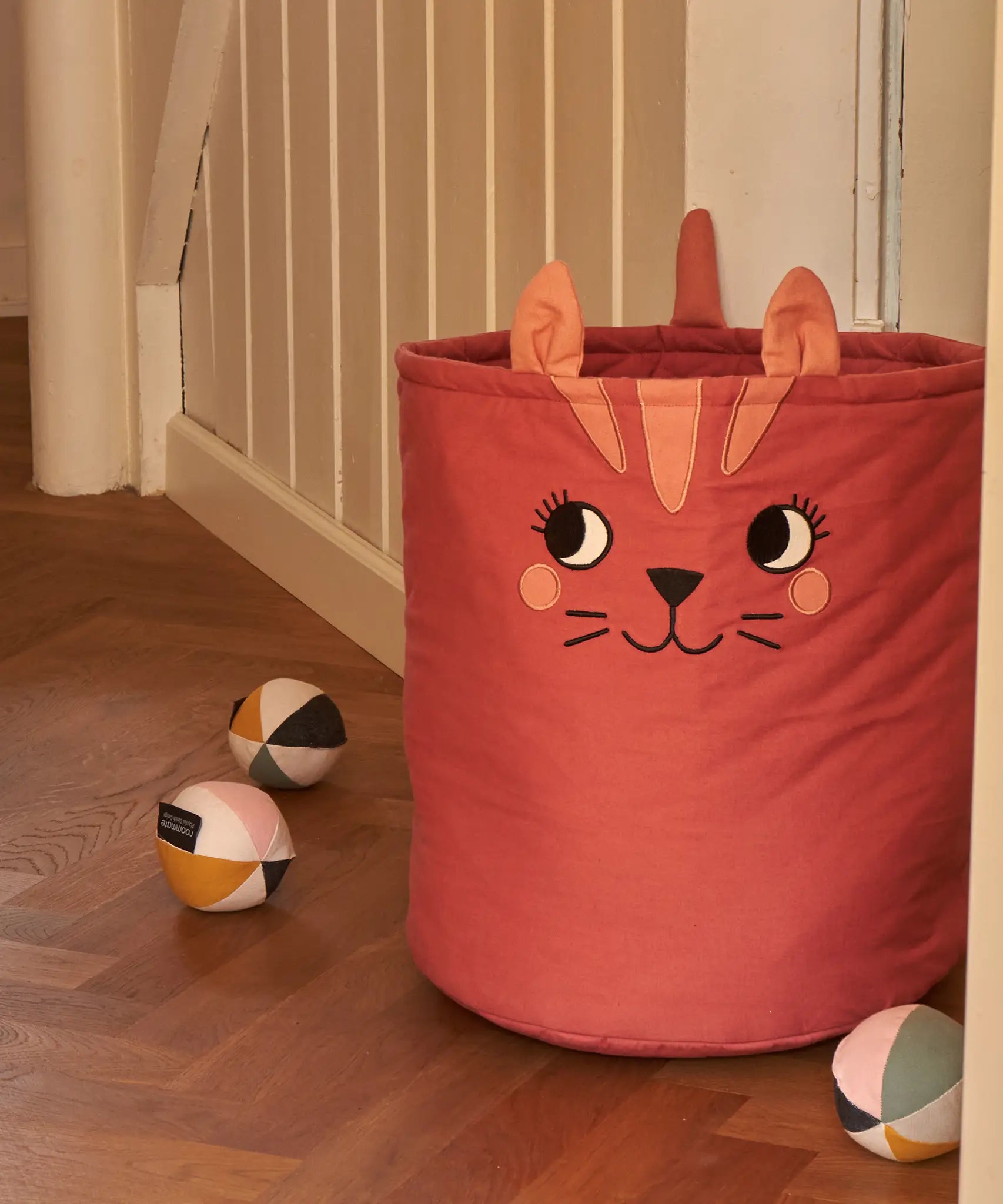 Large Roommate organic cotton storage cat basket in red standing next to sensory balls