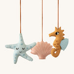 A closer look at the details on the Roommate Sealife Hanging Mobile. The blue starfish has sleepy eyes and dark blue spots. The Pink shell has sleepy eyes and white shell lines, and the sea horse is wide awake with light blue fins on its back